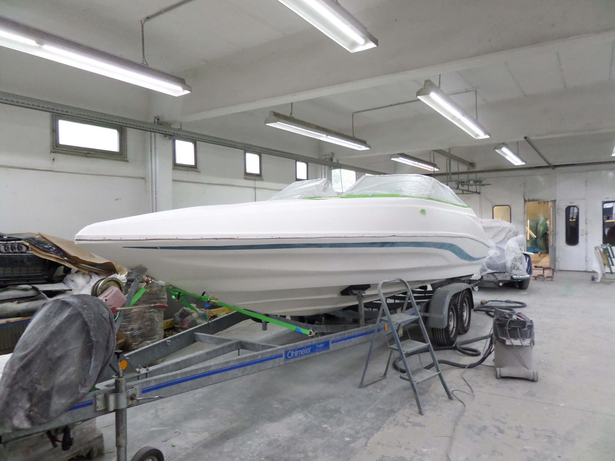 Sportboot im Lackierraum mit frisch lackiertem Rumpf
